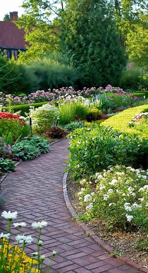 A garden with a brick pathway and white flowers.
