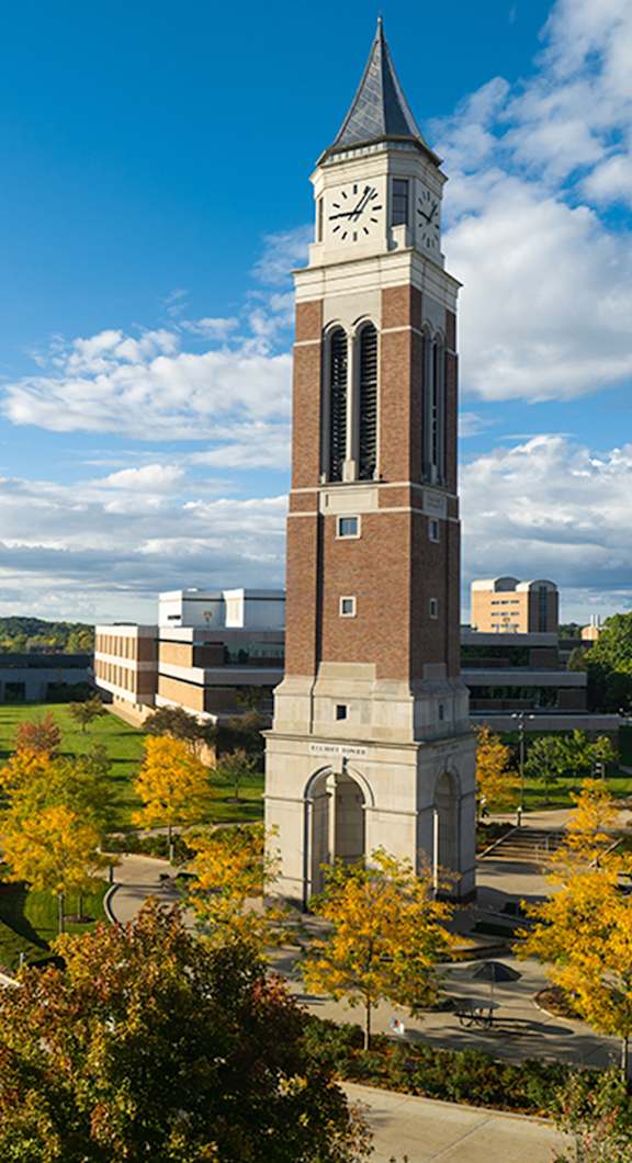A clock tower stands tall in front of a building.