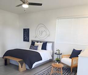 A bedroom with a bed, a bench, and a rug.