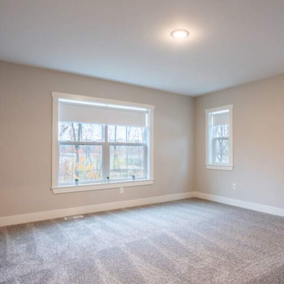 A room with a ceiling fan and a window overlooking a construction site. at Eden Forest Townhomes Apartments, Kentwood , 49508