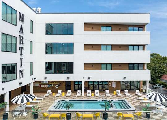 a large hotel with a swimming pool and a patio with yellow chairs
