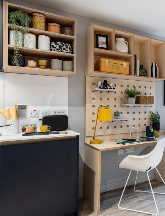a small apartment with a bed and a desk and a kitchen
