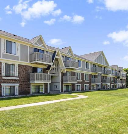 a row of apartment buildings with a green lawn at Briarwood Apartments in Benton Harbor, MI