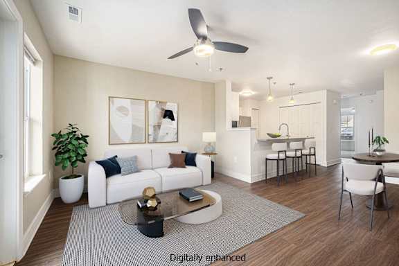 A modern living room with a white sofa, a glass coffee table, and a ceiling fan.