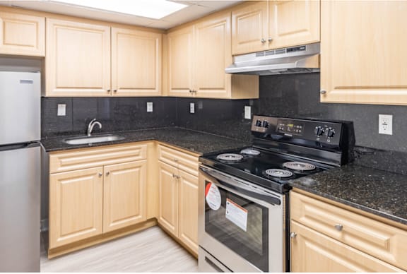 a kitchen with wooden cabinets and black granite countertops at Lakeside @ Biscayne Gardens,North Miami, FL,33181