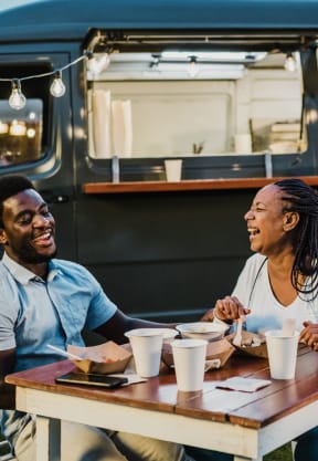 a couple sitting at a table in front of a food truck