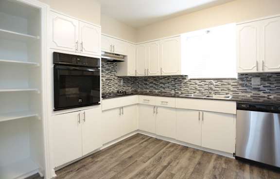 A kitchen with white cabinets and a black stove top oven.