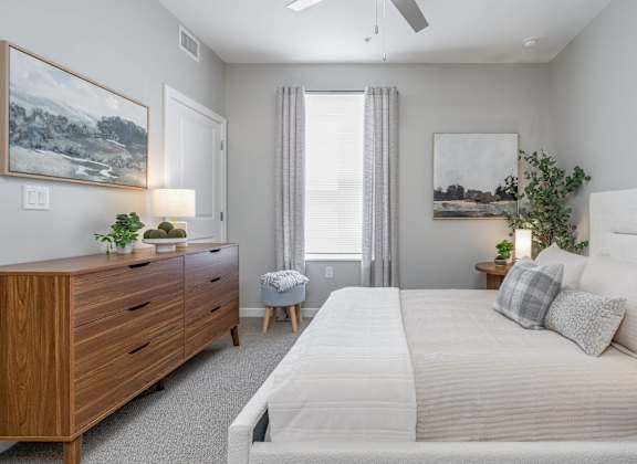A bedroom with a large bed, a dresser, and a painting on the wall.