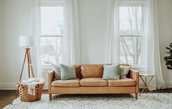 A living room with a tan couch, a white rug, and a white floor lamp.