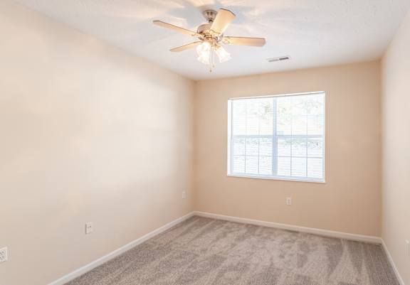 A room with a ceiling fan and a window.