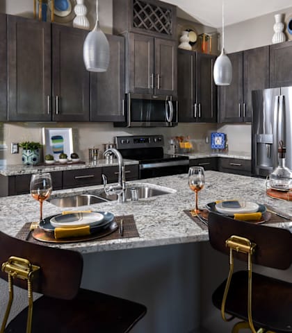 a kitchen with dark cabinets and a large island with a granite countertop