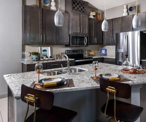 a kitchen with dark cabinets and a large island with a granite countertop