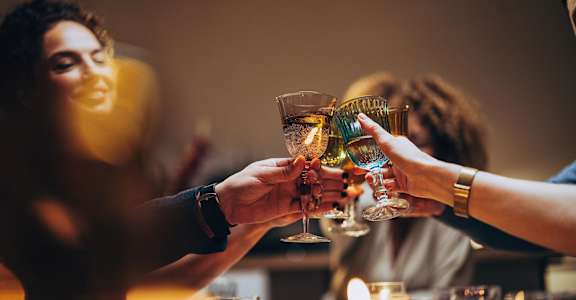 people raising their wine glasses at a dinner party
