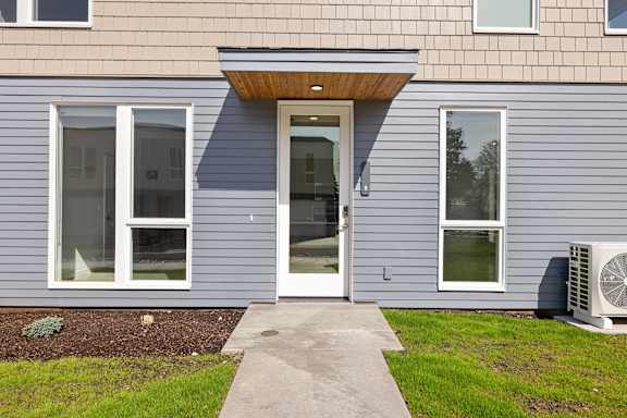 the front of a house with blue siding and a white door