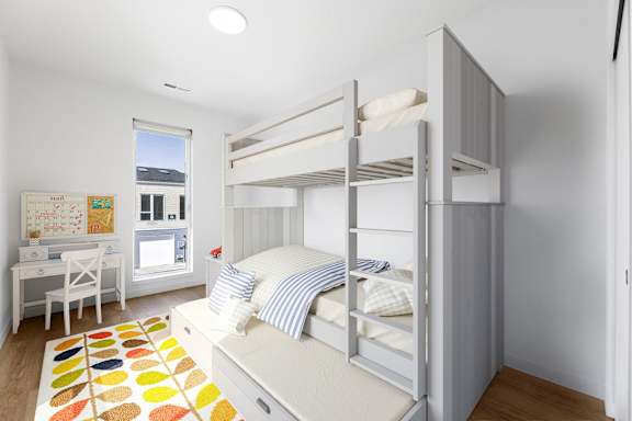 a bedroom with bunk beds and a desk and a window