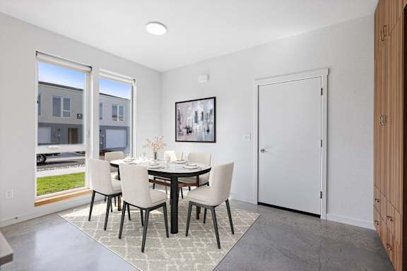 a dining room with a table and chairs and a door to a hallway