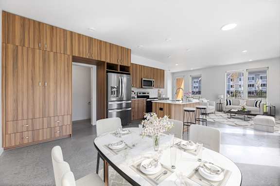 a dining room with a table and chairs and a kitchen with stainless steel appliances