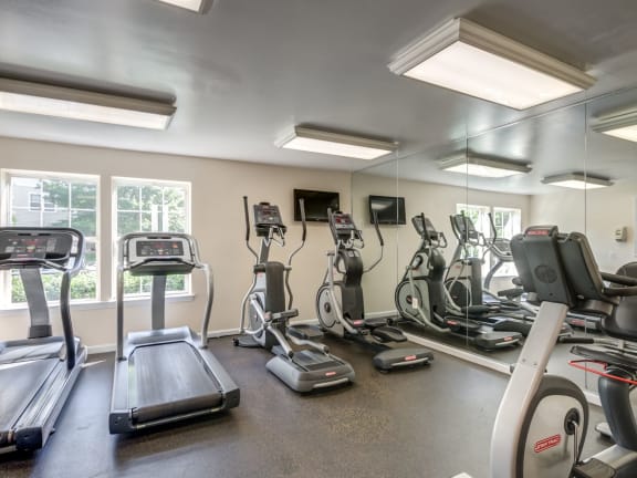 a gym with various cardio equipment and mirrors on the wall  at Sanger Place, Virginia