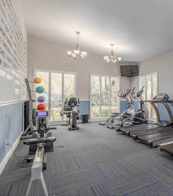 A gym with a wall of inspirational quotes and exercise equipment.