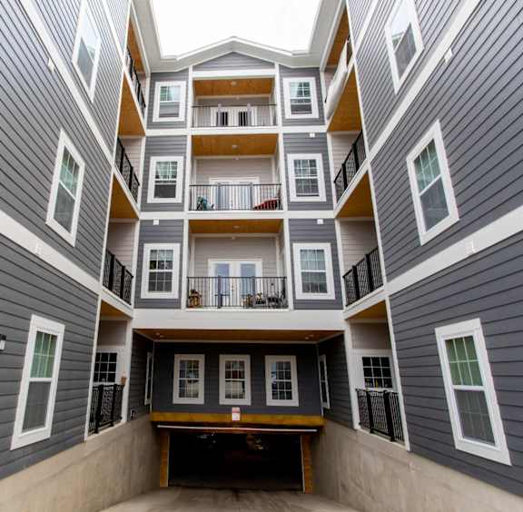 A view from the bottom of a multi-story apartment building looking up towards the balconies.