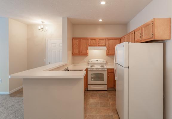 A kitchen with a white refrigerator, sink, and stove.