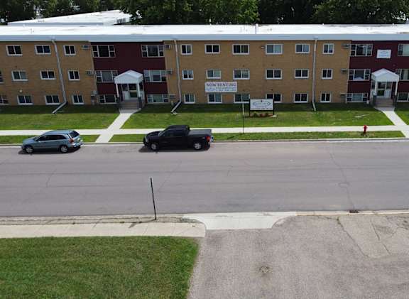 A parking lot in front of a multi-story apartment building