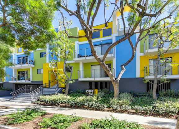 Blue/Yellow/Green Apartment Exterior with View of Private Patio, Trees, Bushes at Croft Plaza Apartments, West Hollywood, 90069