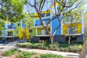 Blue/Yellow/Green Apartment Exterior with View of Private Patio, Trees, Bushes at Croft Plaza Apartments, West Hollywood, 90069