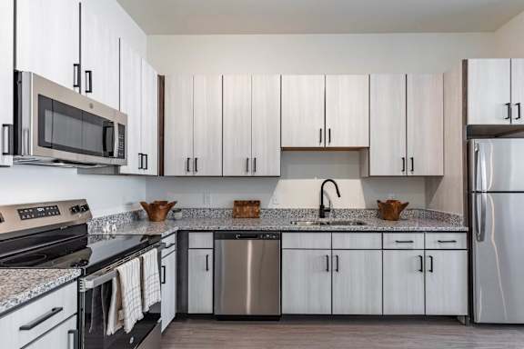 A modern kitchen with a black stove and white cabinets.