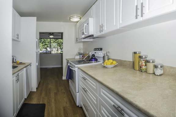 a kitchen with white cabinets and counter tops and a sink