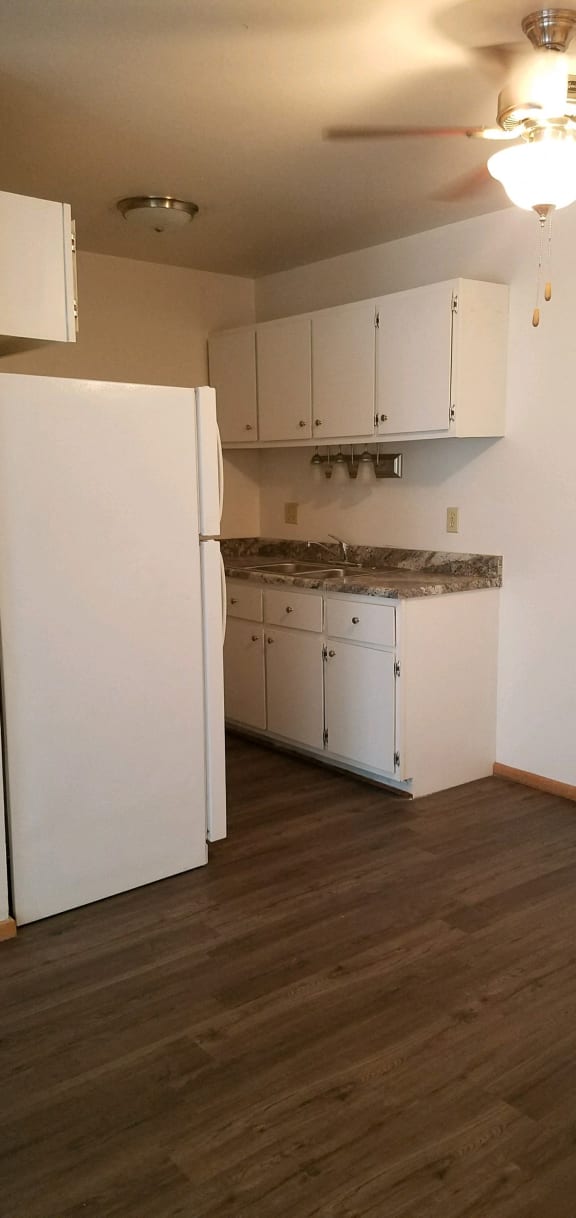 an empty kitchen with white cabinets and a ceiling fan