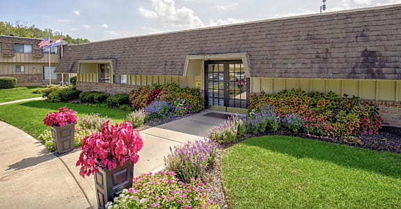 a sidewalk in front of a building with flowers and plants