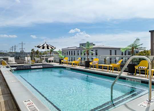 a swimming pool with yellow chairs and a building in the background