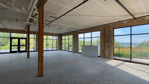 an empty room with glass windows and a view of the woods