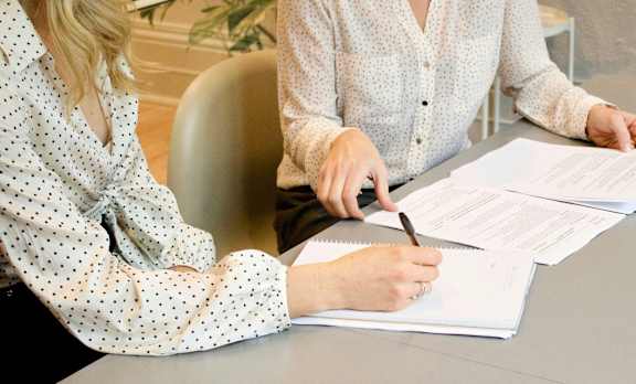 two women sitting at a table signing documents