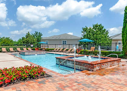 A pool area with a hot tub and lounge chairs.