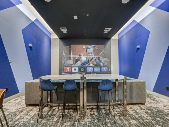 a room with a table with four chairs and a projection screen on the wall at Icon One, Daytona Beach, FL, 32114