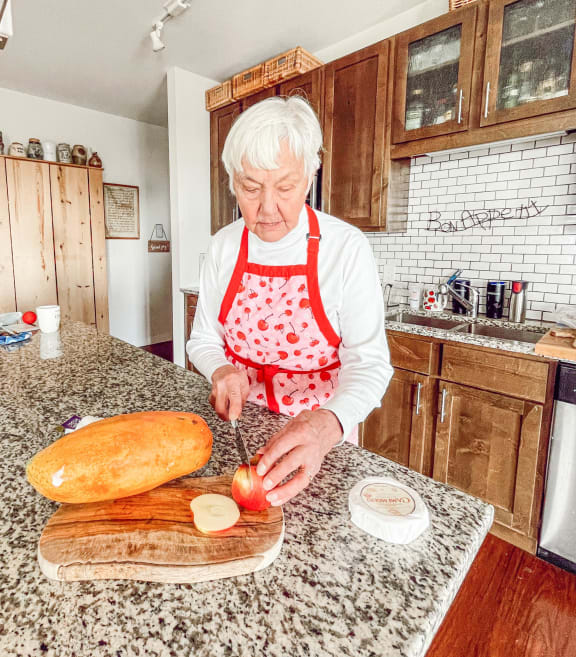 an older woman in a kitchen preparing food on a cutting board at Bluestone Flats, Duluth, 55803