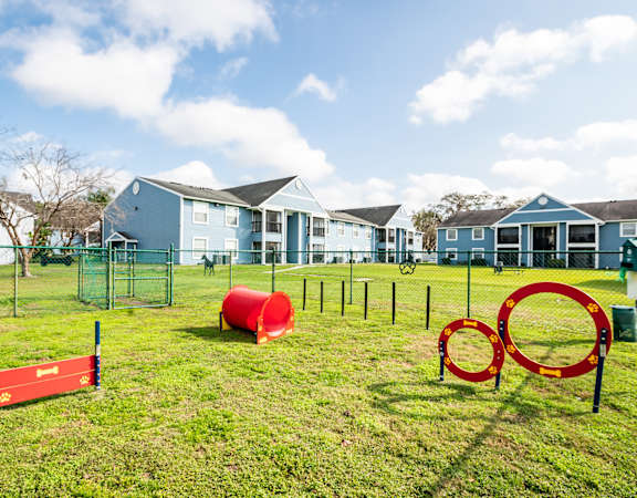 a playground with agility equipment and houses in the background