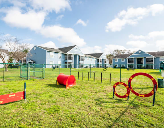 a playground with agility equipment and houses in the background
