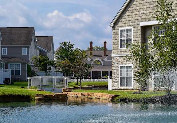 This is a picture of a fountain in a pond with building exteriors at Nantucket Apartments, in Loveland, OH.