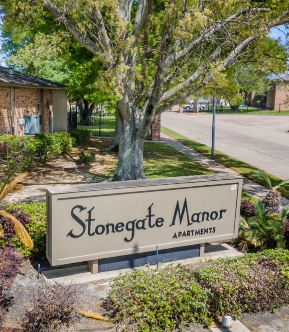 a sign that says stonegate manor apartments in front of a brick building