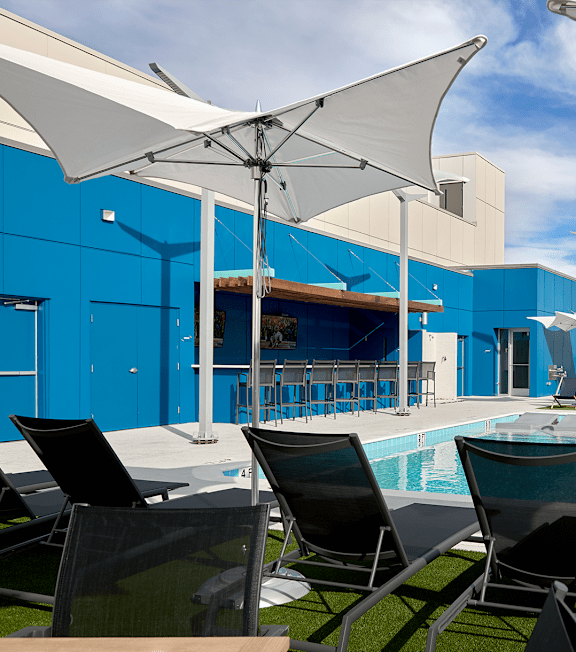 a swimming pool with chairs and umbrellas and a building in the background at Link Apartments® Canvas, Atlanta, GA, 30312