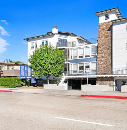 A white building with a red stripe in front of it at Toluca Court, Toluca Lake, CA