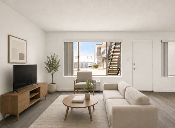 A living room with a television, a chair, a coffee table, and a staircase in the background.