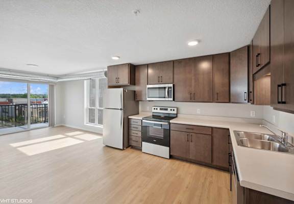 an open kitchen and living room with dark wood cabinets and white countertops