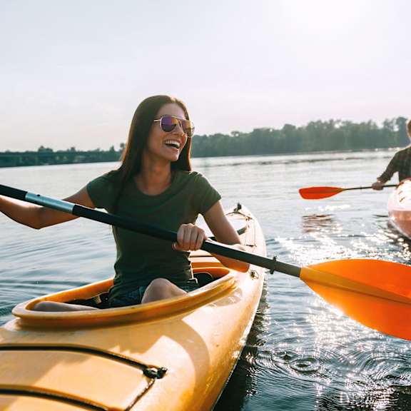 Two people kayaking on a calm body of water.