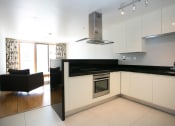 Thumbnail 2 of 3 - a kitchen with white cabinets and a black counter top