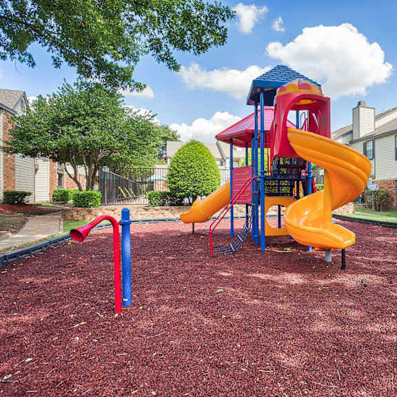 A playground with a red slide and a yellow slide.
