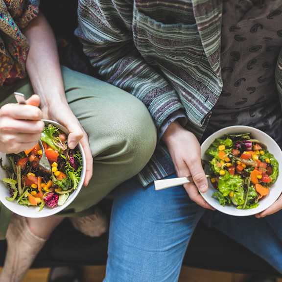 Two people eating salads together.